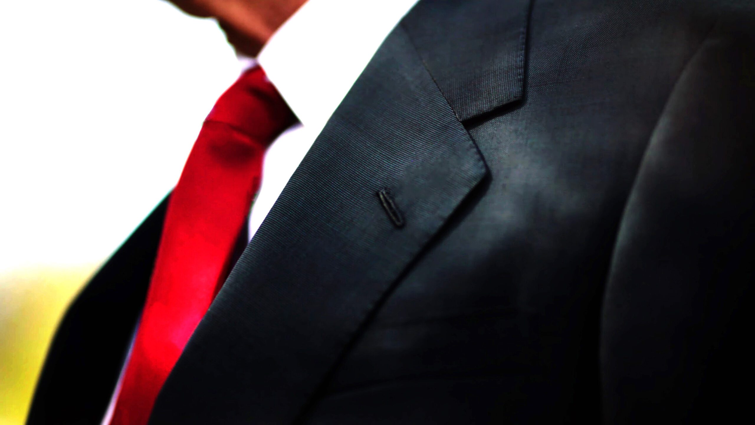 a black business suit jacket with white shirt and red tie man n